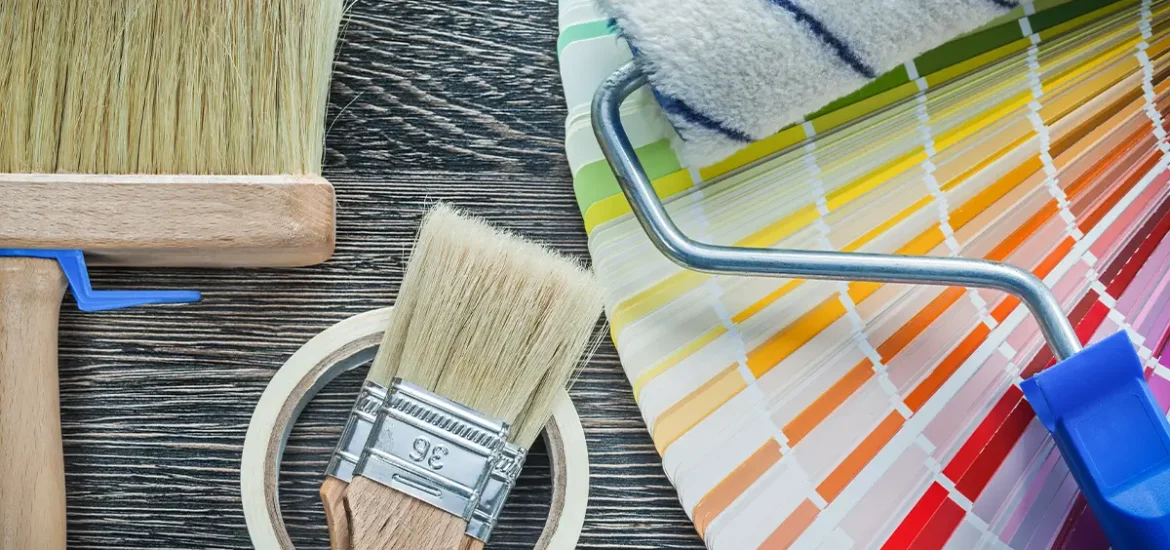 Painting supplies with color swatches on a wooden surface.