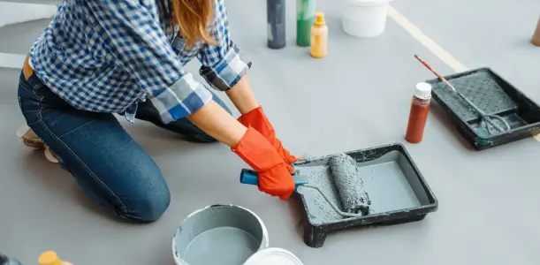 Woman preparing to paint, pouring paint into a roller tray.