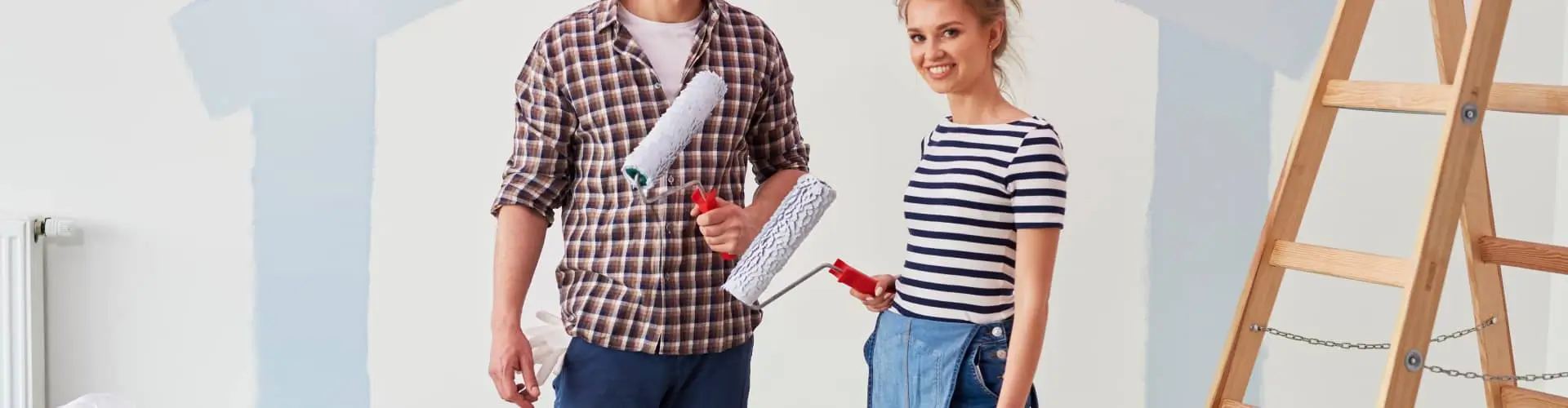 Two people standing with paint rollers ready for home improvement.