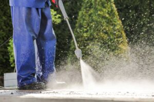 Person using a high-pressure washer to clean a surface.