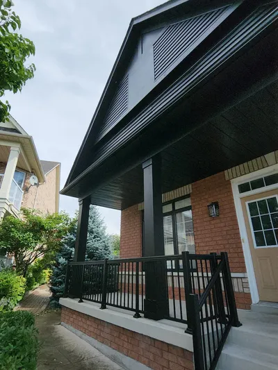 Modern house with a brick facade, black railings, and a covered porch.