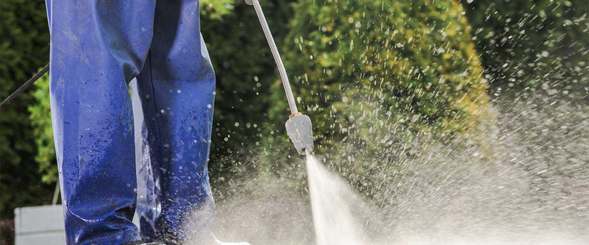 Person using a high-pressure washer to clean a surface.